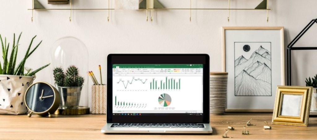 Computador em secretária com gráficos no Excel